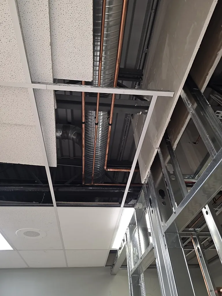 Copper hot water mains supported and routed clear of ductwork above a commercial ceiling by PeakFlow Plumbing Calgary