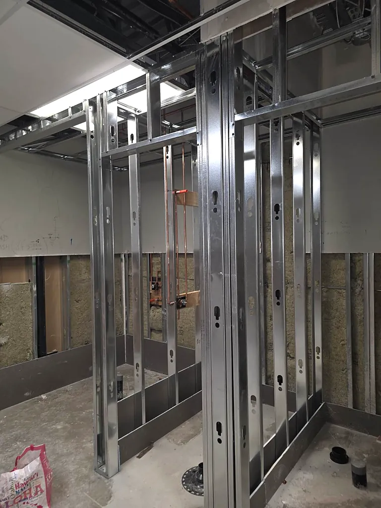 Commercial shower stalls framed with floor drains and waterproofing base by PeakFlow Plumbing Calgary