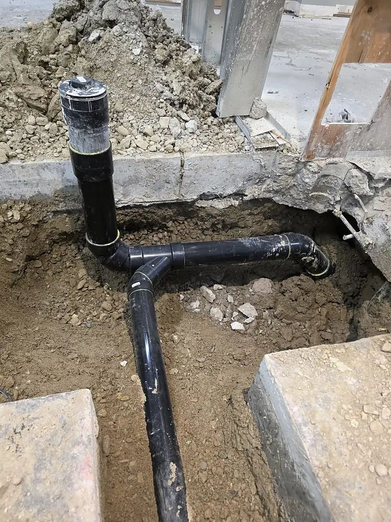 Underground drainage cleanout riser and sweep fittings installed by PeakFlow Plumbing Calgary